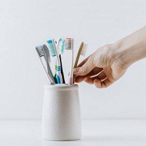 Hand reaches for toothbrush in toothbrush holder