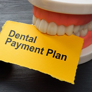 Artificial teeth on desk biting yellow paper that says “Dental Payment Plan”