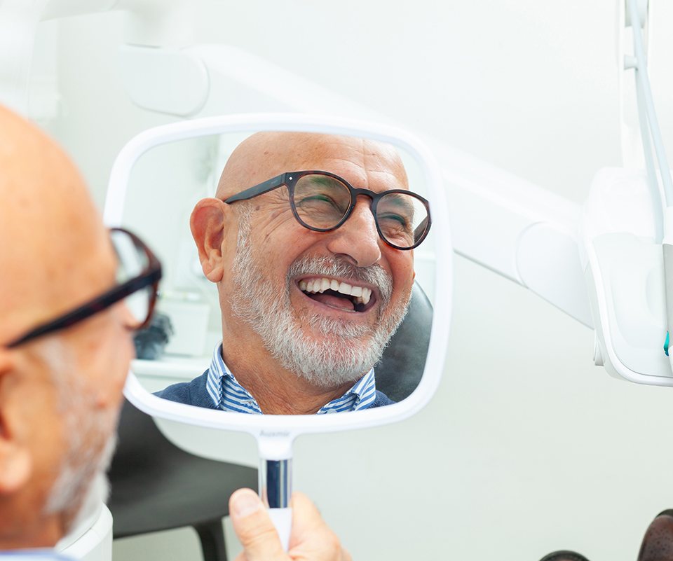 Dental patient’s smiling face reflected in mirror