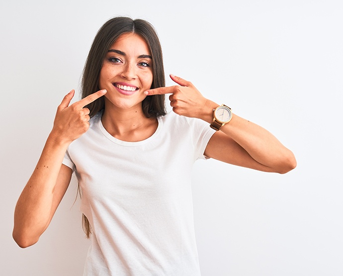 Woman in white t-shirt pointing at her smile