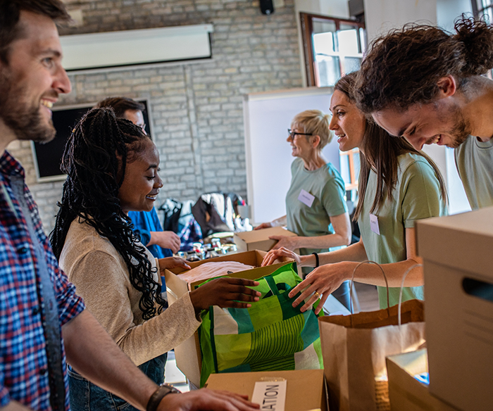 Multiple people standing around table with bags