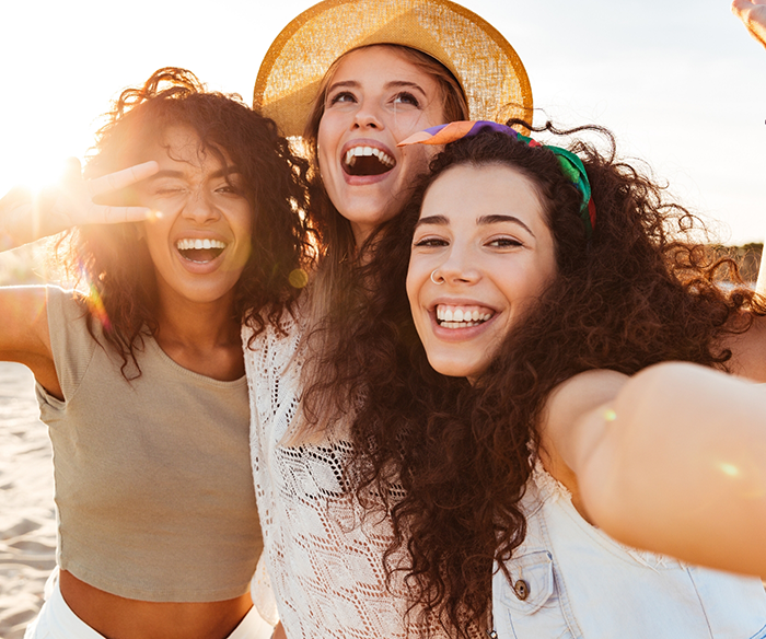 Three women standing together outside and smiling