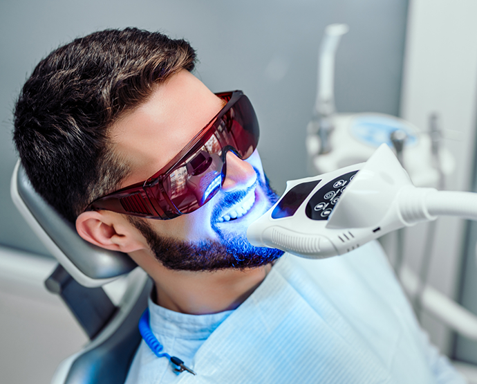 Man sitting in dental chair receiving teeth whitening