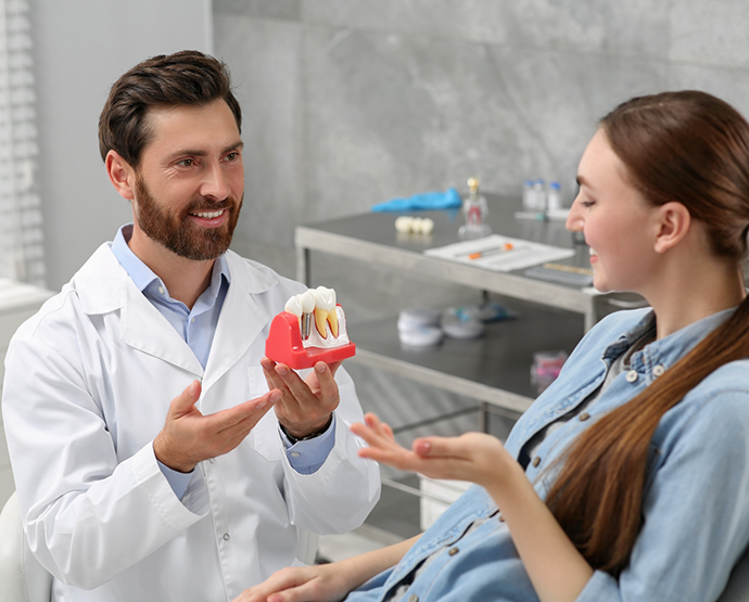 Dentist showing dental implant model to patient