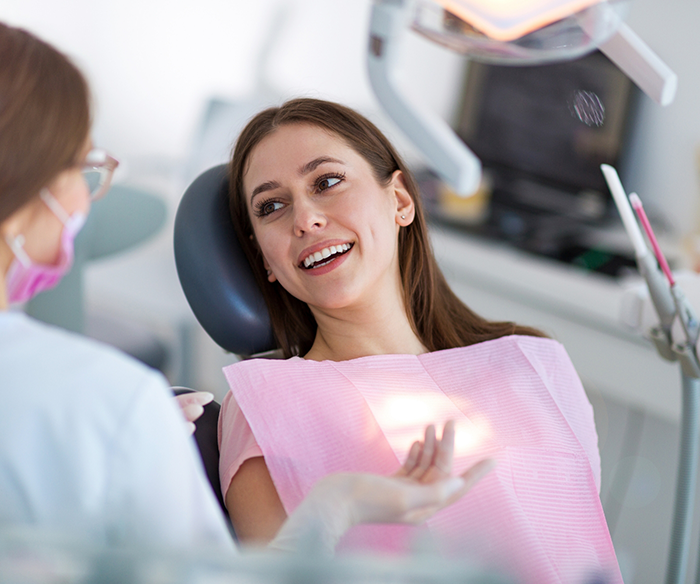 Woman sitting in dental chair looking to side and smiling