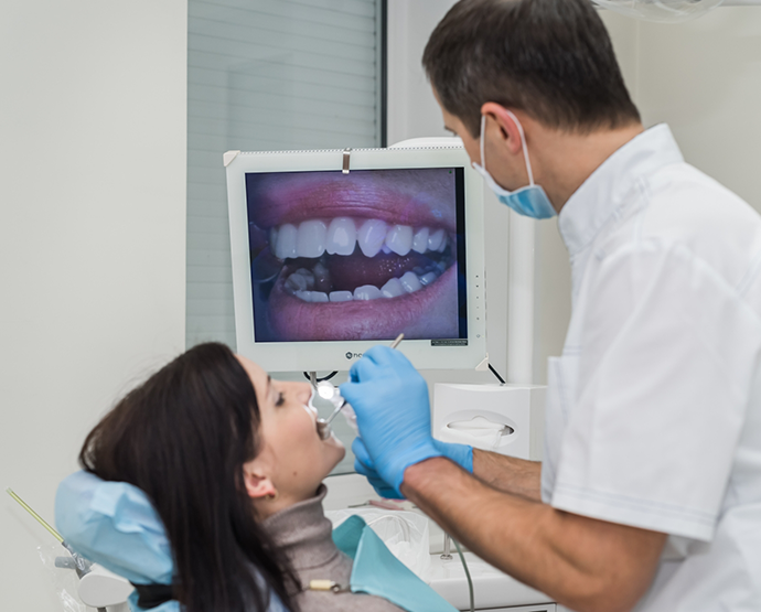 Dentist looking at monitor while examining patients mouth with camera