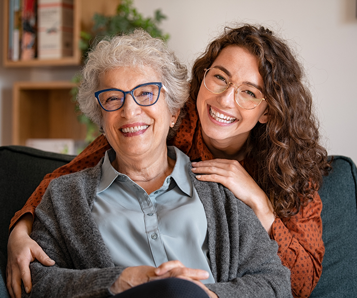 Senior woman smiling with other woman smiling from behind her