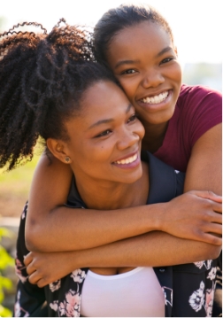 Woman hugging another woman from behind outside
