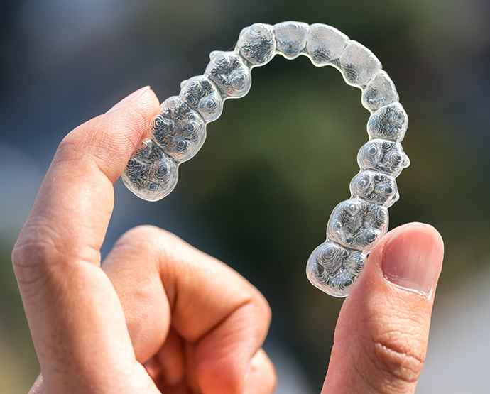 Close up of hand holding a clear aligner