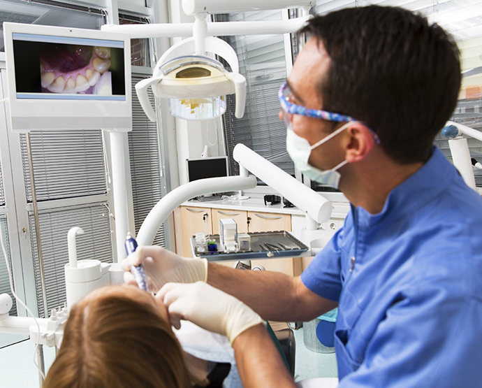 Dentist looking at monitor while scanning patients teeth