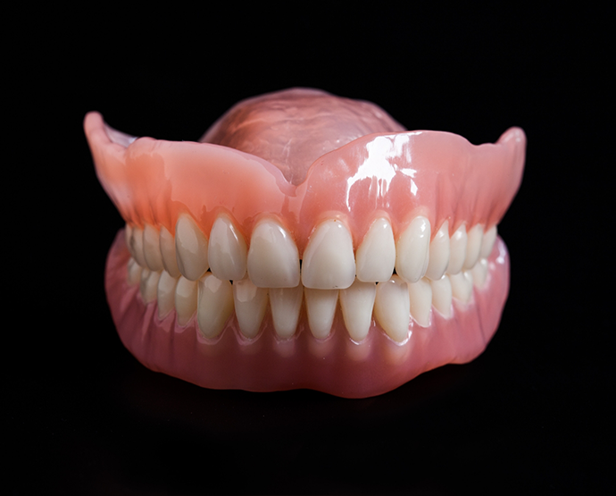Close up of full dentures against black background