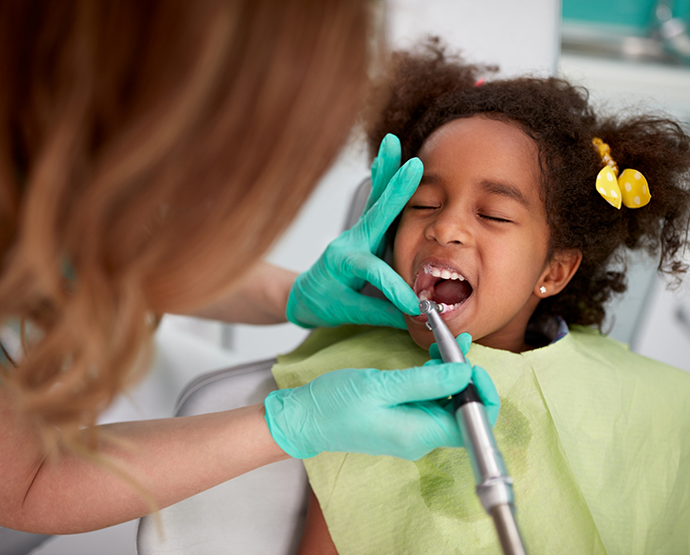 Little girl holding mouth open for dental cleaning