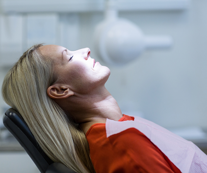 Woman with eyes closed leaning back in dental chair