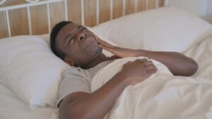 Man lying in bed with toothache. 